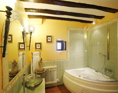 baño de habitacion de paredes amarillas con una bañera de hidromasajes triangular en un hotel en Azofra, La Rioja