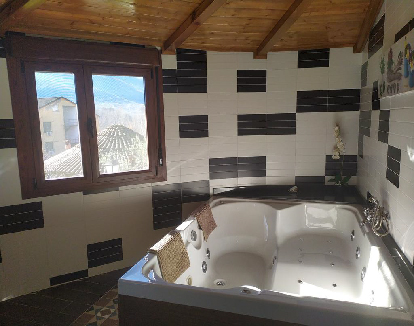 baño de apartameto con ceramica en las paredes y un jacuzzi para 2 con bañera de hidromasaje en un complejo en Jerte, Cáceres