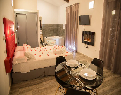 habitacion con paredes claras una cama matrimonial al lado de un closet y un jacuzzi privado en la esquina de la habitacion en un hotel en Santa Cruz de la Sierra, Cáceres