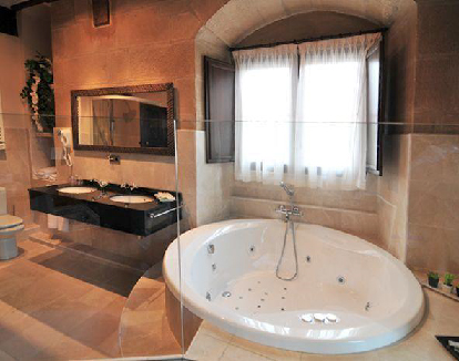 baño de habitacion con paredes de ladrillos con una bañera d hidromasajes redonda en un hotel en Zarratón, La rioja