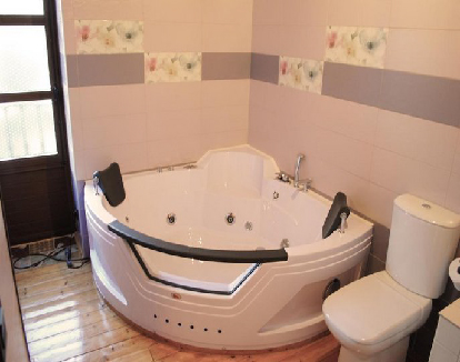 baño con paredes claras y decoradas y una bañera triangular blanca en un hotel en Pajares de los Oteros