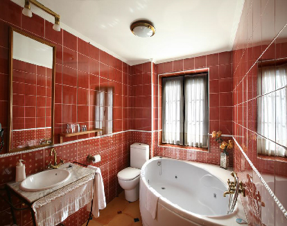 baño de habitacion con paredes de ceramica roja y una bañera de hidromasaje redonda en un hotel en San Millán de la Cogolla, La rioja