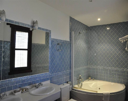 baño de habitacion con ceramica azul y una bañera de hidromasaje triangular en un hotel en Garganta la Olla, Cáceres