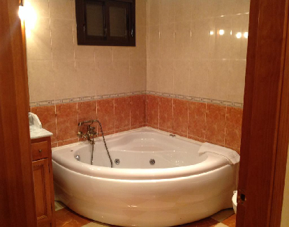 suite con paredes con ceramica y una bañera de hidromasaje triangular en un hotel en Trujillo, Cáceres