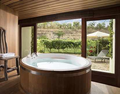 Foto de baño de madera con ventanal de vidrio y Jacuzzi de madera y creamica blanca de forma redonda en este hotel de encanto