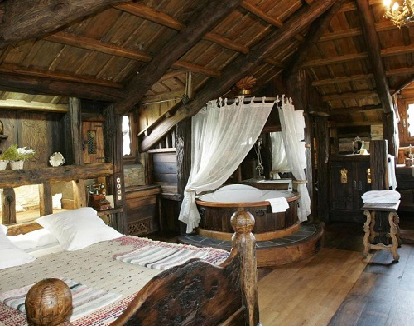 habitacion de madera con cama de madera y jacuzzi privado circular recubierto de madera en un hotel en canedo