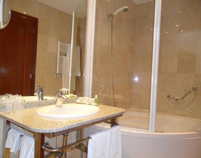 baño con paredes claras con bañera de hidromasajes rectangular rectangular con cristales en un hoten en Ponferrada