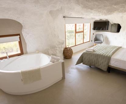 Foto de la bañera de hidromasaje junto a la ventana y cerca de la cama en el dormitorio de la casa túnel Nido de Águilas