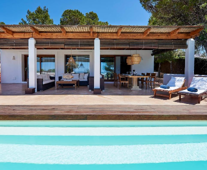 Foto de Villa Can Mares tomada desde la piscina, donde se observa la sona de estar y área de barbacoa.