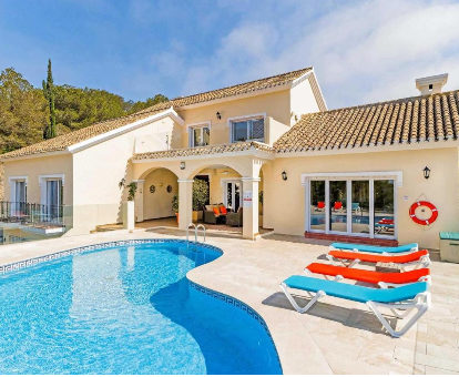 Foto de Villa El Forestal donde se observa su hermosa piscina, tumbonas y la parte exterior de la villa.