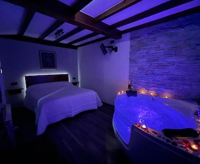 Foto del jacuzzi para dos personas con lunes iluminando su interior y que se encuentra frente a la cama en el apartamento La Era de Lario