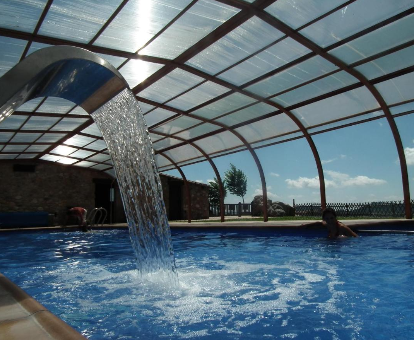 Foto de la piscina cubierta climatizada con cascada y luz natural