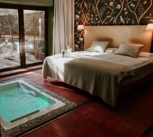 Jacuzzi cuadrado lleno de agua y funcionando a ras de suelo frente a la cama en el dormitorio de la suite en el hotel Hotel Boutique Pinar