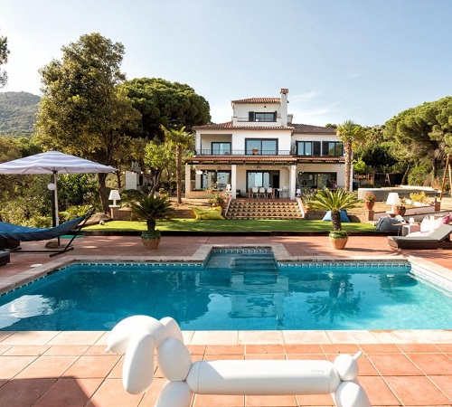 Foto de la piscina con mobiliario de jardín y césped con pinos al fondo en la Villa Costa Barcelona